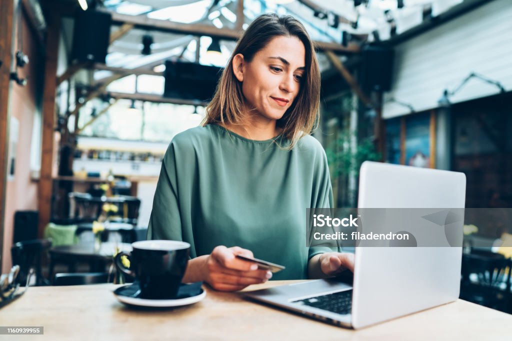 Online shopping Young woman shopping online in cafe using lap top and credit card Internet Stock Photo