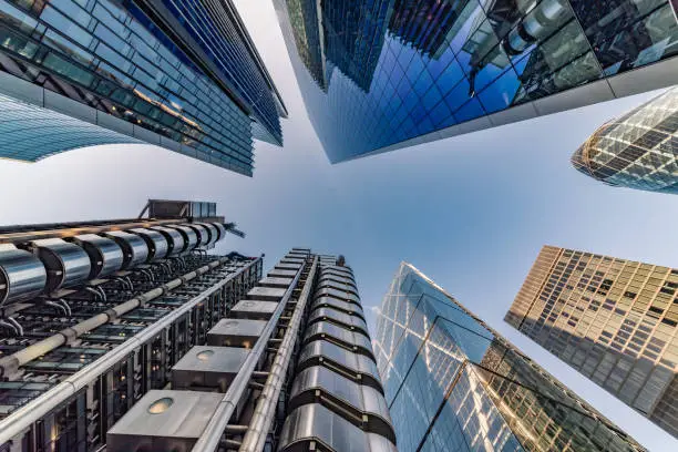 Highly detailed abstract wide angle view up towards the sky in the financial district of London City and its ultra modern contemporary buildings with unique architecture. Shot on Canon EOS R full frame with 14mm wide angle lens on a clear sunny day. Image is ideal for background with copy space.