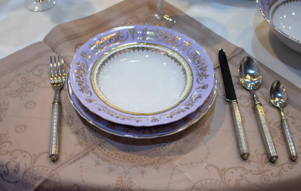 istock Lilac purple plate with cutlery on a linen napkin. Table setting. Rough plate fork knife cutlery spoon dessert spoon. The festive table is covered with a white tablecloth with linen napkins. 1160943163