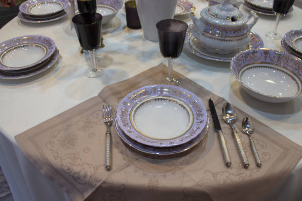 istock Festive table setting, purple white set. White linen tablecloth, purple plate cutlery. Deep plates glasses spoons forks knives tureen 1160943176