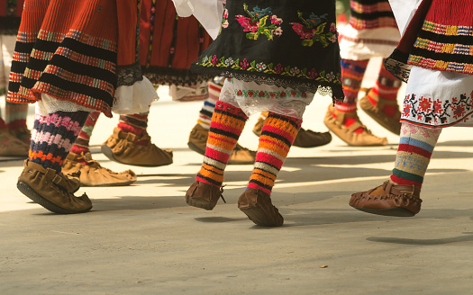 Chicas bailando danza folclórica. La gente con trajes tradicionales bailan bailes folclóricos búlgaros. Primer plano de las piernas femeninas con zapatos tradicionales, calcetines y disfraces para bailes folclóricos. photo