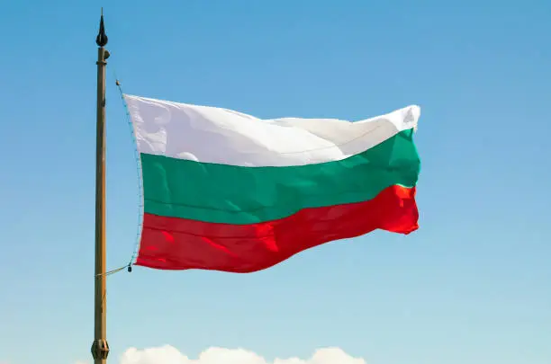Photo of The Bulgarian Flag over the Memorial of Liberty Shipka, Gabrovo, Bulgaria. The national flag of Bulgaria against the background of the blue sky.