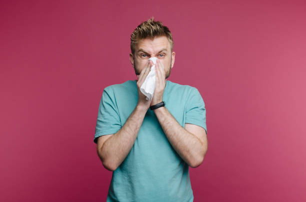 istock studio picture from a young man with handkerchief. Sick guy isolated has runny nose. man makes a cure for the common cold 1160943656