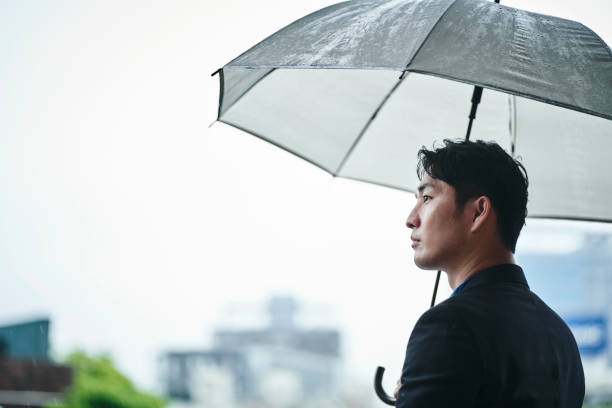 istock Thoughtful businessman with umbrella against sky 1160947279
