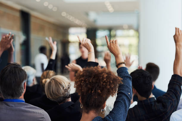 You learn through asking Shot of a group of businesspeople raising their hands to ask questions during a conference asking stock pictures, royalty-free photos & images