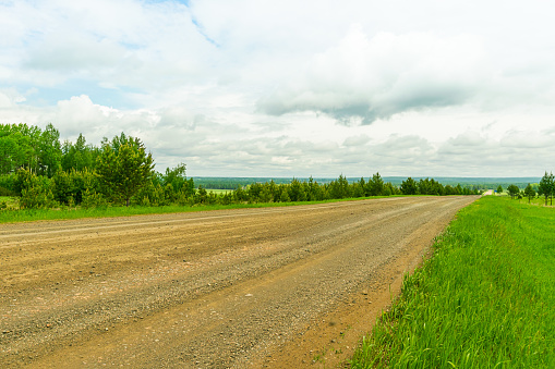Landscape rural road and blue sky. Straight gravel road leading to the horizon. Horizontal frame.