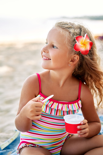 Young girl listening to a seashell.