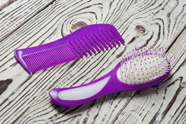 istock Two different purple plastic hair brushes on old weathered white wooden table 1160955589
