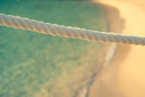 Closeup of White Rope With Turquoise Sea and White Sand in the Background
