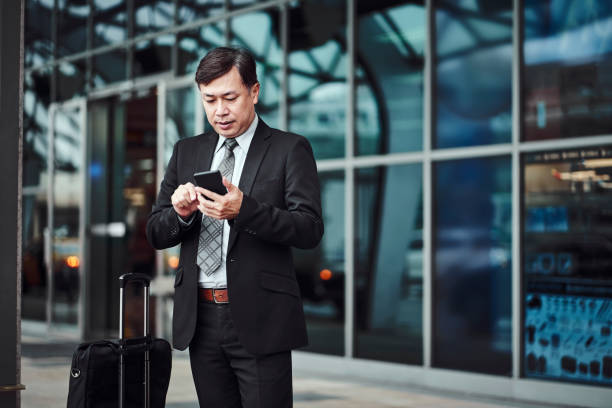 istock Businessman using smart phone outside airport 1160960844