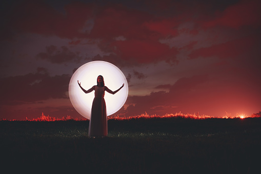 Young woman silhouette and moon. Light painting.