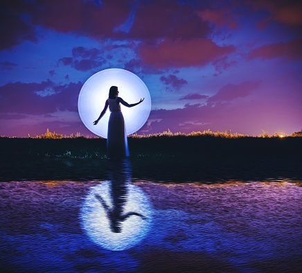 Young woman silhouette and moon. Light painting.
