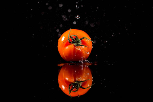 istock The tomato with drops stands on the black background 1160963467