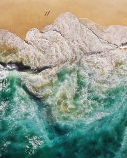 海岸で壊れるターコイズブルーオーシャン波を示す人里離れたビーチの人々のトップ航空写真 - nusa lembongan bali island beach ストックフォトと画像