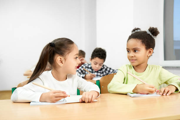 istock Cheerful classmates sitting at table in classroom at school 1160964770