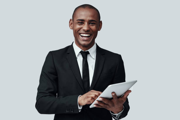 istock Young and smart. Young African man in formalwear looking at camera and smiling while standing against grey background 1160964902