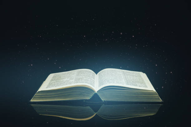 istock Open Holy Bible on a black glass table dark background 1160965623