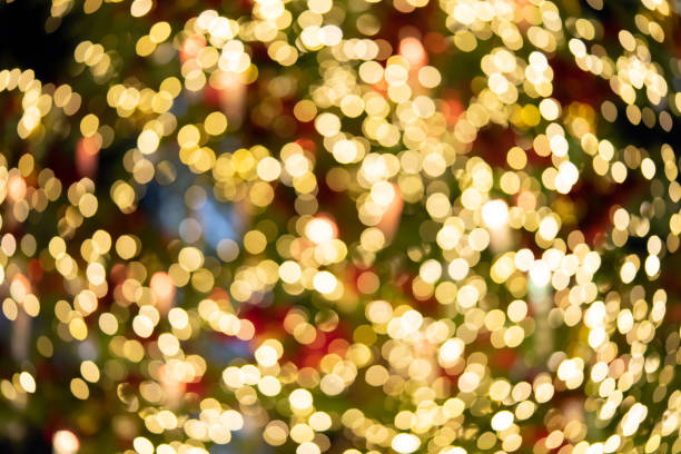 luzes bokeh da árvore de natal é iluminada a partir de vários satélites. apropriado para o uso como um fundo na propaganda dos meios. - gold bright brightly lit light - fotografias e filmes do acervo