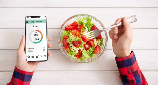istock Male hands using smartphone and eating fresh salad 1160967883
