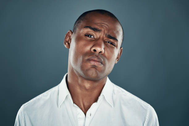 istock Confident look. Handsome young African man in shirt looking at camera and frowning while standing against grey background 1160969456