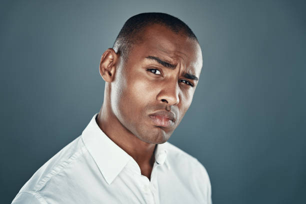 istock Masculinity. Handsome young African man in shirt looking at camera and frowning while standing against grey background 1160969715