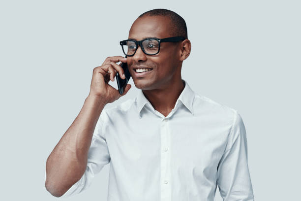 istock Pleasant talk. Handsome young African man talking on the smart phone while standing against grey background 1160972888