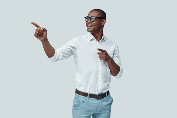 istock Look over there! Handsome young African man pointing copy space and smiling while standing against grey background 1160973654