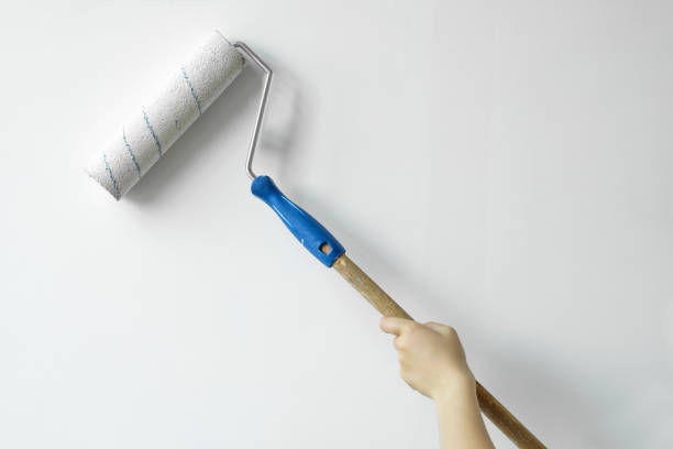 istock A hand with a roller paints the wall with white paint. Decorator's hand painting wall with roller 1160974397