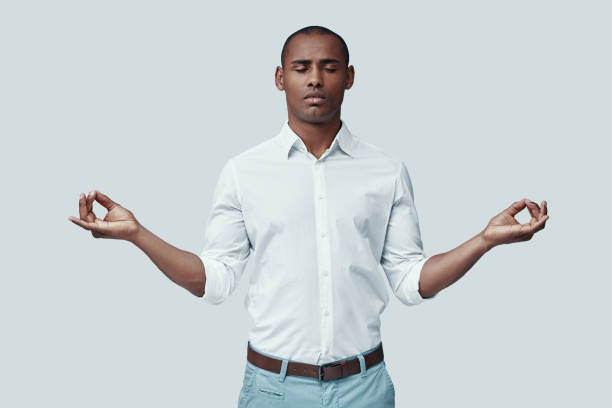 istock Find your balance. Handsome young African man meditating while standing against grey background 1160974435