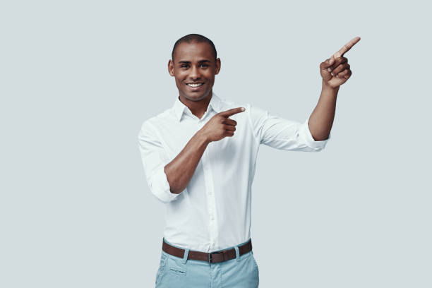 istock Here is something special. Handsome young African man pointing copy space and smiling while standing against grey background 1160975099