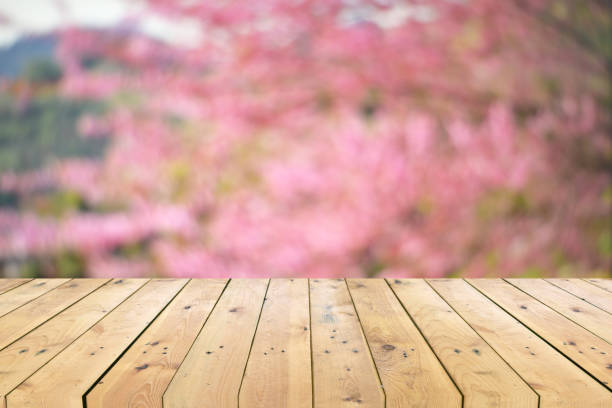 istock Empty wooden table top with colorful floral blurred background 1160978507