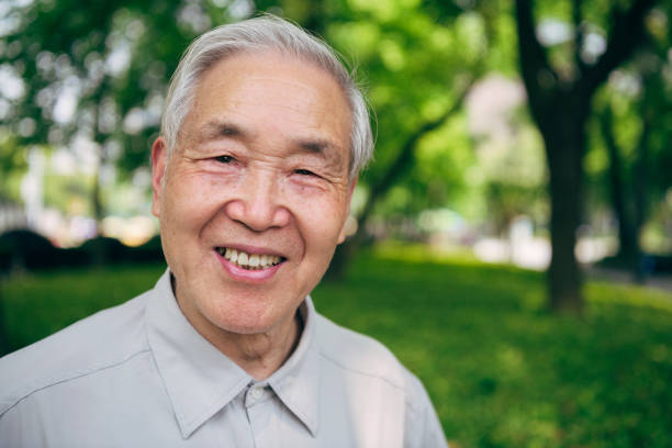Portrait of a relaxed and smiling senior Chinese man enjoying a walk through a lush Shanghai public park.