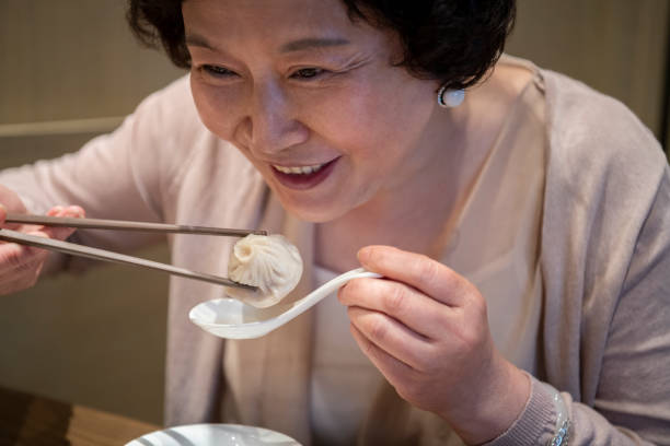 istock Smiling Senior Chinese Woman Enjoying a Restaurant Dumpling 1160979666