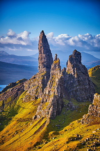 View Over Old Man Of Storr, Isle Of Skye, Scotland. During a beautiful sunrise and dramatic sky with a local shower here and there. The Old Man of Storr looms over Portree, Isle of Skye and is situated 7 miles north of the town. It is dominated by the 50 metre high petrified lava pinnacle of the Old Man of Storr, with a brutal tumble of cliff behind, and the panorama spreads across loch, sea and islands to the high mountains of the mainland beyond.