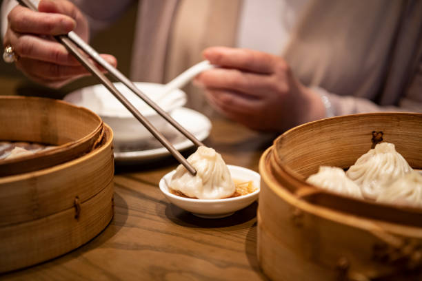 istock Chinese Woman Dipping Dumpling into Sauce with Chopsticks 1160979717