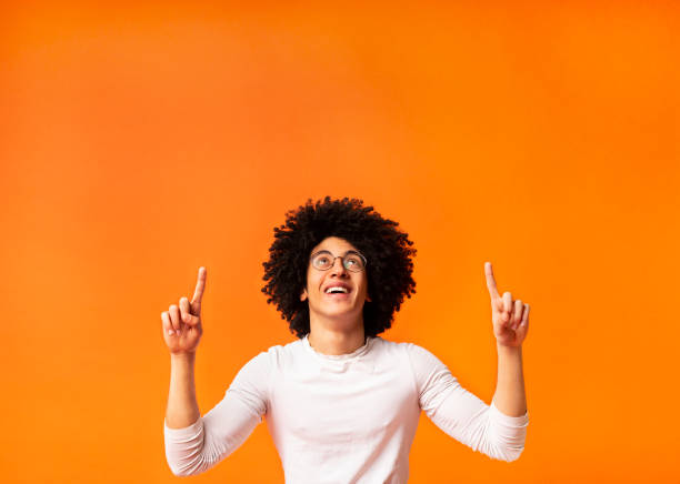 Stylish black man in glasses pointing away at empty space