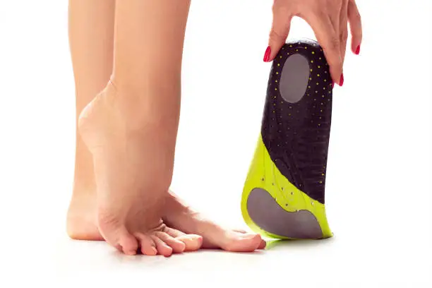 female feet stand on their toes and orthopedic insole in the hand