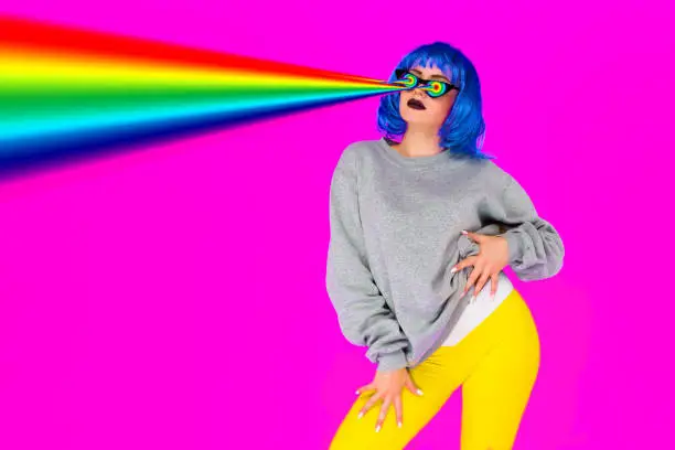 Photo of Lesbian girl in blue wig and sunglasses shoots from her eyes rainbow lasers on a pink background