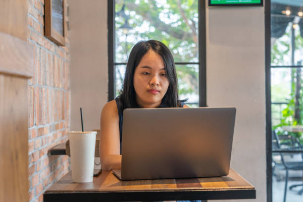istock Young Asian woman working on laptop at coffee table 1160992141