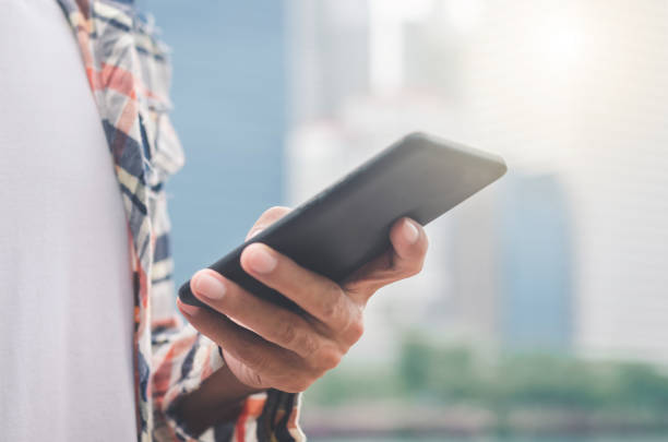 istock close up handsome man using hand typing mobile phones and touch screen working search with app devices outdoor in city with sunrise and building background. 1160992852