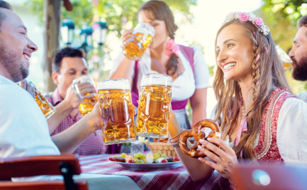 пара звон бокалов с огромным количеством пива в баварском пабе - german culture people women germany стоковые фото и изображения