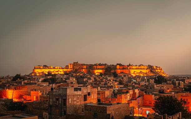 Jaisalmer fort and surrounding houses at dusk, Rajasthan, India. Jaisalmer, Rajasthan, India. Jaisalmer fort and surroinding houses lit up by flood lights at dusk in the Thar desert, Jaisalmer, Rajasthan, India. rajasthan stock pictures, royalty-free photos & images