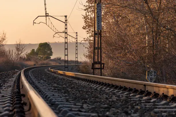 Unique railroad line at the sunset. Train railway track. Low clouds over the railroad.