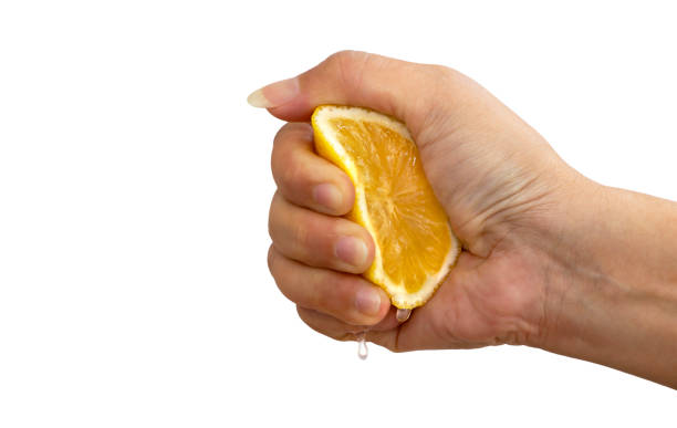 istock Women's hand squeezing a half of fresh lemon yellow on a white background. 1160996696