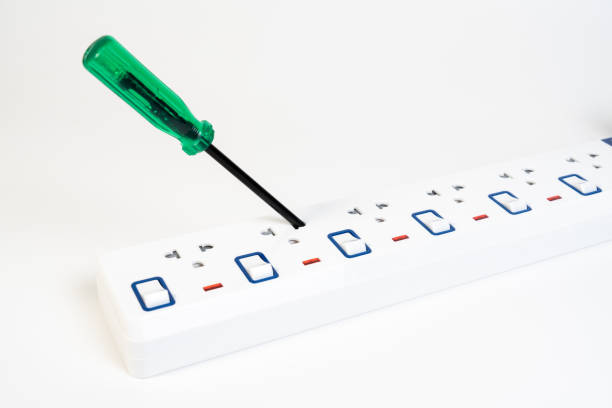 electrician put screwdriver into portable multiple socket outlet switch and plug on white background. - misapplication imagens e fotografias de stock