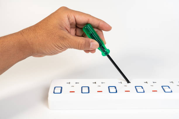 hand holding screwdriver and put into portable multiple socket outlet switch and plug on white background. - misapplication imagens e fotografias de stock