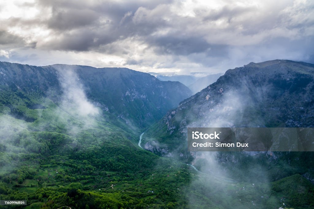 Montenegro, Aerial perspective view over endless green tara river canyon nature landscape with some clouds from summit of mount curevac in durmitor national park near zabljak Above Stock Photo