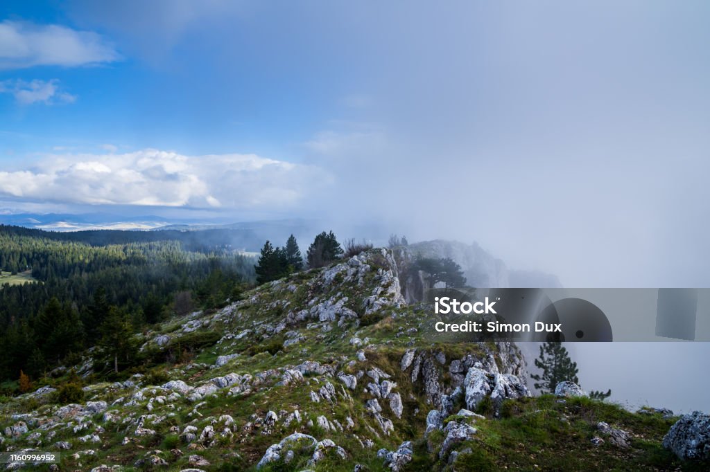 Montenegro, Weather contrast of blue sky versus foggy rain clouds coming and changing fast on summit of mount curevac after adventurous hike through durmitor national park highlands to the edge of tara river canyon Alpine climate Stock Photo