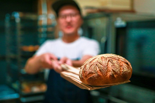 Young man is making bread own their shop