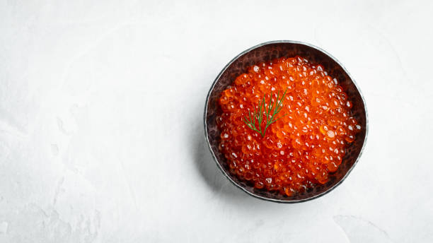 istock Delicious red caviar in black bowl on a light concrete background. Top view with copy space. Flat lay 1160999251